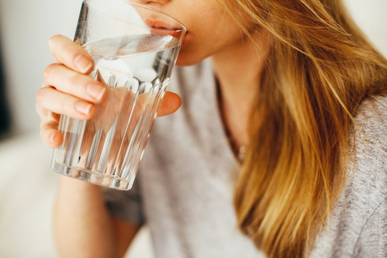 Jeune femme qui boit un verre d'eau